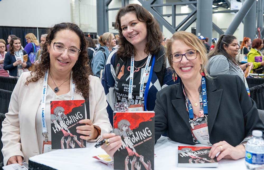 Three women, an author and two attendees at the Authors Area book signing area at TLA Annual Conference