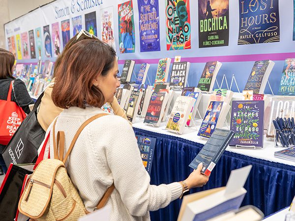 Attendee looking at a book in an exhibitor booth in the TLA exhibit hall
