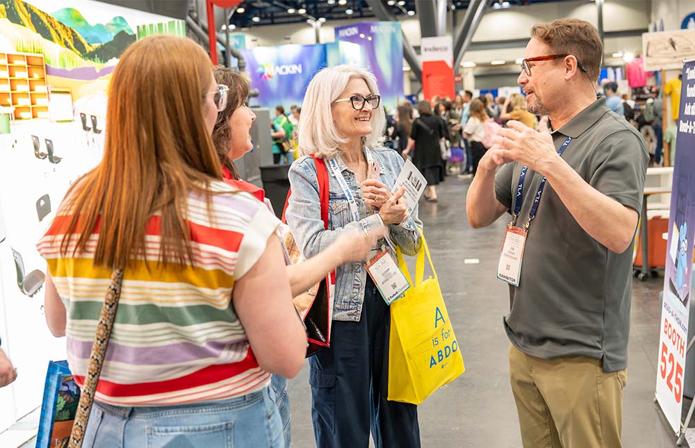 Three women talk with a male exhibitor in the TLA Annual Conference Exhibit Hall.