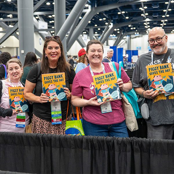 Four attendees, three women and one man holding books in the TLA Authors Area in the Annual Conference exhibit hall.