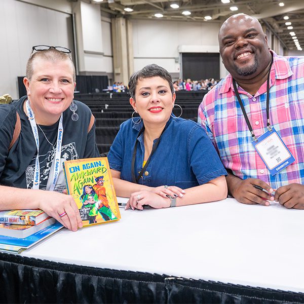 Two authors with an attendee holding a book at the Authors Area book signing at TLA Annual Conference