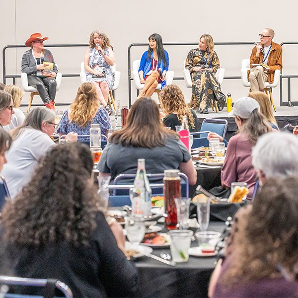 Evening With The Authors panel onstage with audience at tables.