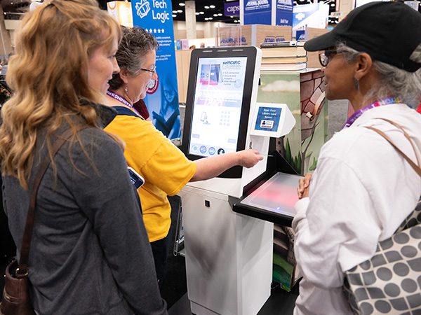 Exhibitor demonstrating book checkout equipment to TLA attendees