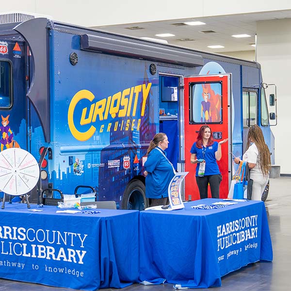 Harris County Public Library Curiosity Cruiser large panel truck with two staff and an attendee.