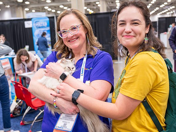 Two women holding kitten in TLA Exhibit Hall