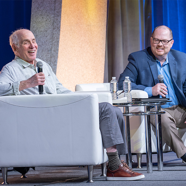 Louis Sachar-TLA 2025 Keynote sitting in a chair with interviewer on stage at TLA's Annual Conference