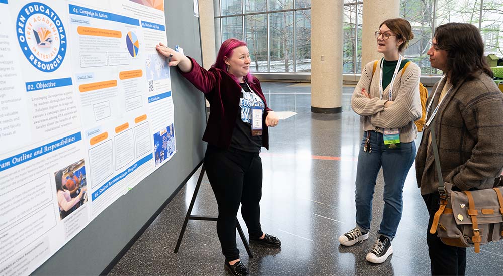 Female presenter at TLA Poster Session with two female attendees.