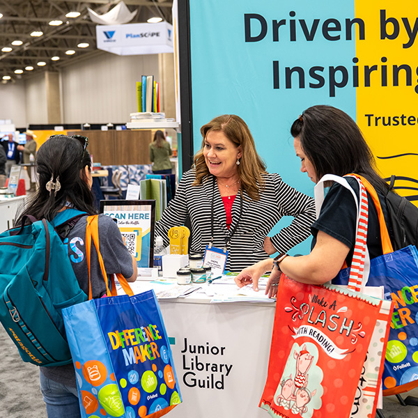 TLA 2025 Exhibit Hall Booth with two women attendees talking with vendor