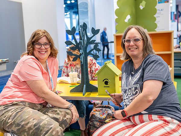 Two female attendees sitting in The Lawn area at the TLA 2026 Annual Conference.
