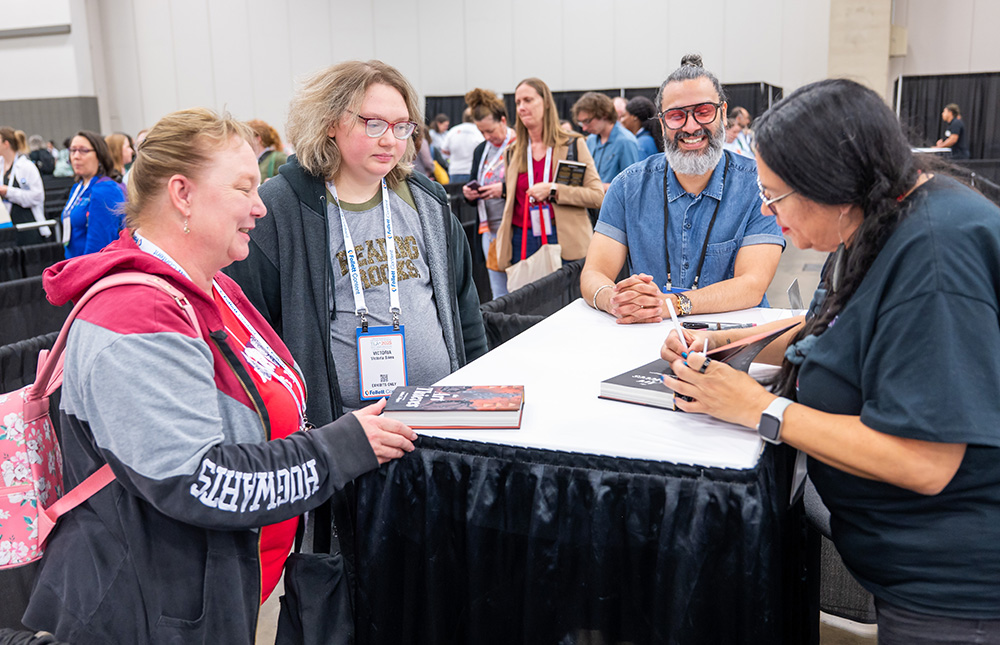 Group of attendees getting books signed by author at TLA Annual Conference Authors Area