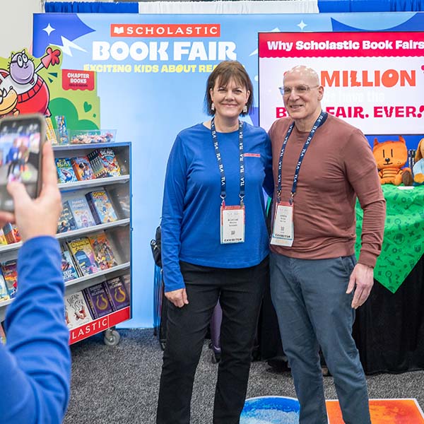 Female TLA attendee with author Gordon Korman getting a photo together.