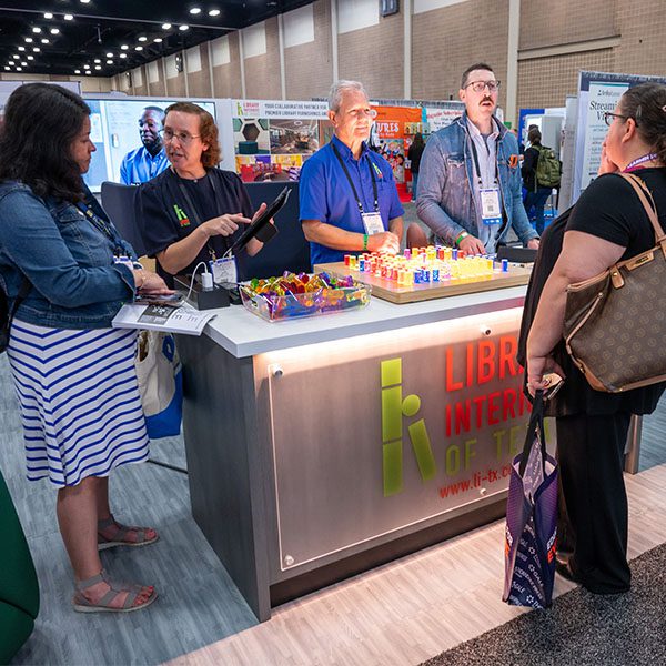 Two TLA attendees meeting with exhibitors in the TLA Annual Conference exhibit hall.