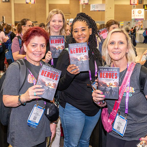 Four TLA attendees holding books in the Authors Area of the TLA Exhibit Hall.