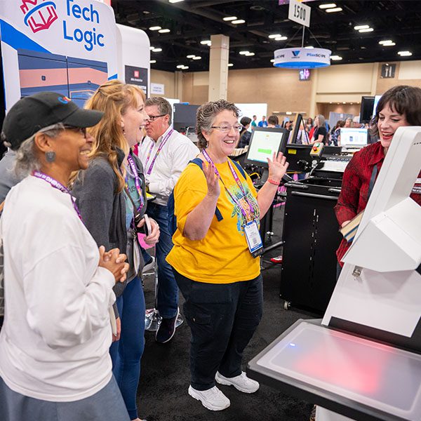Three attendees learning from an exhibitor at the TLA Annual Conference.